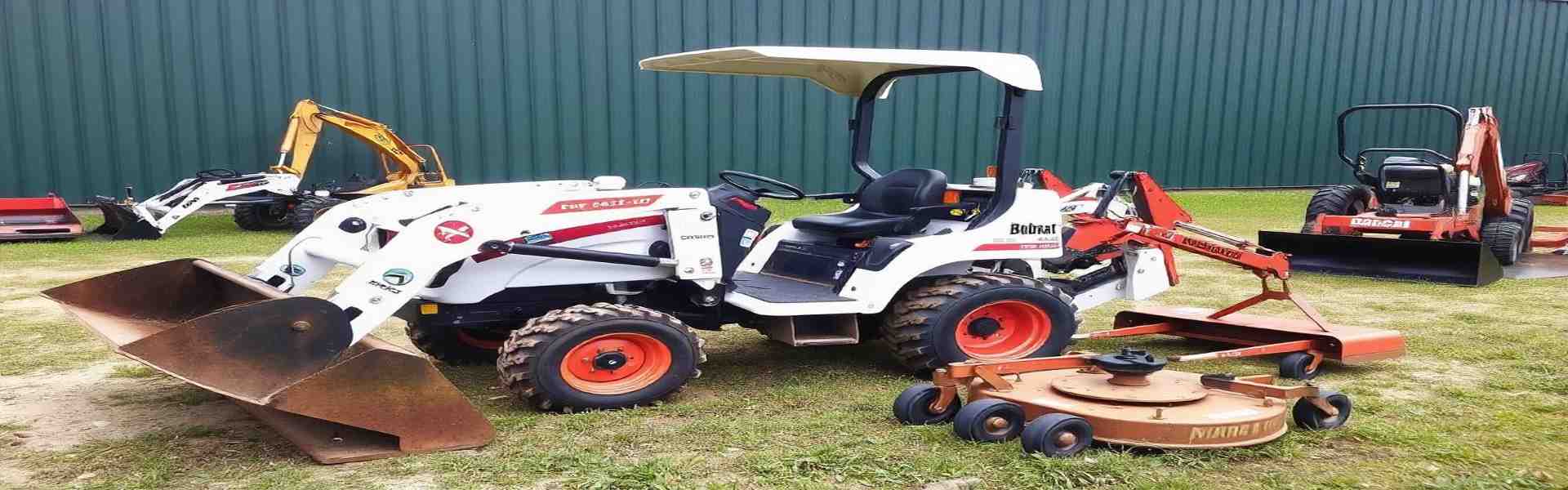 Bobcat compact tractor equipped with various attachments including a loader, backhoe, and mower for multiple tasks.